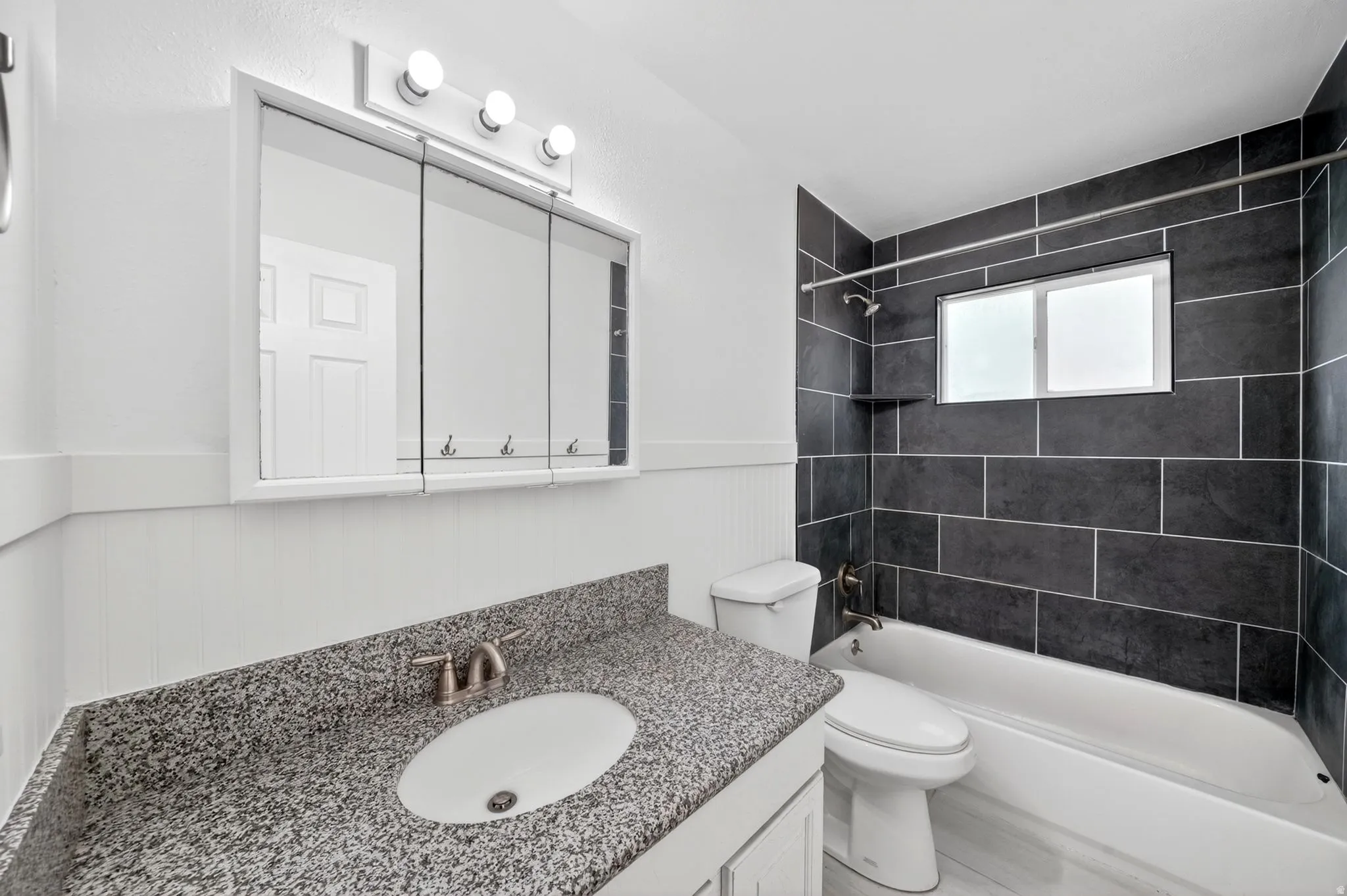 Bathroom featuring a white vanity with a granite-style countertop, undermount sink, and brushed nickel faucet