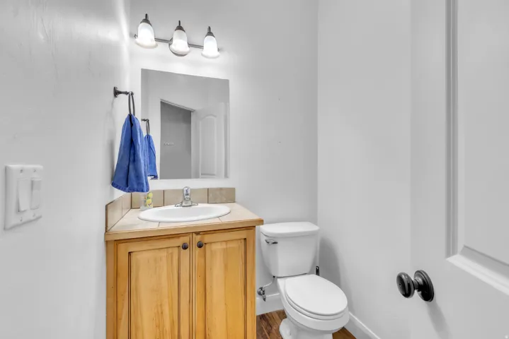 Bathroom featuring a wooden vanity with integrated sink, ceramic tile countertop, and contemporary three-light fixture