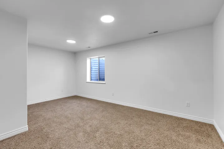 Spacious room featuring neutral carpet flooring, white painted walls, and white baseboards