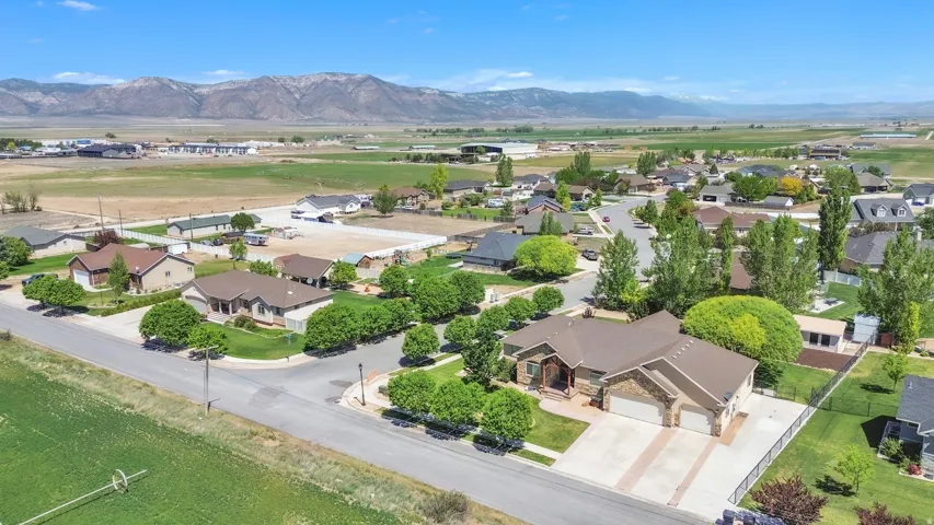 Aerial perspective showcasing a residential neighborhood with surrounding fields and distant mountains