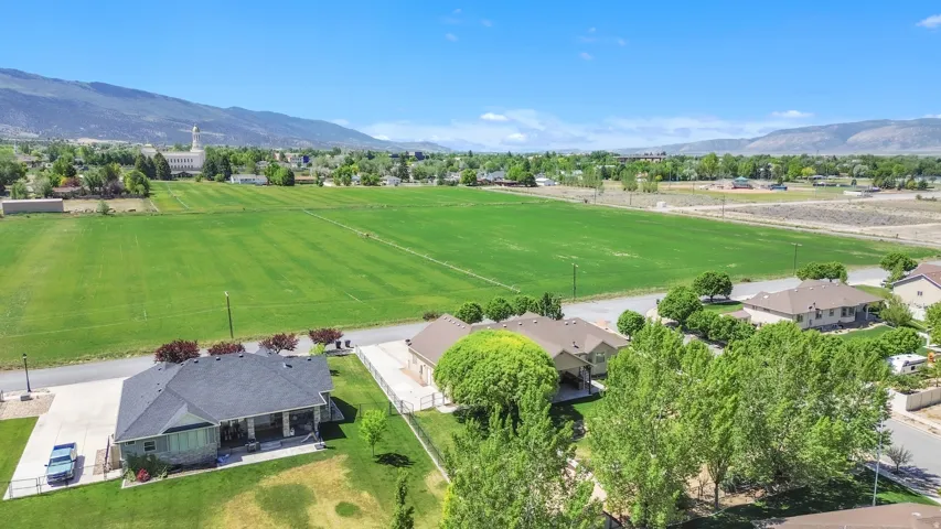 Expansive green fields bordering a residential area with distant mountains