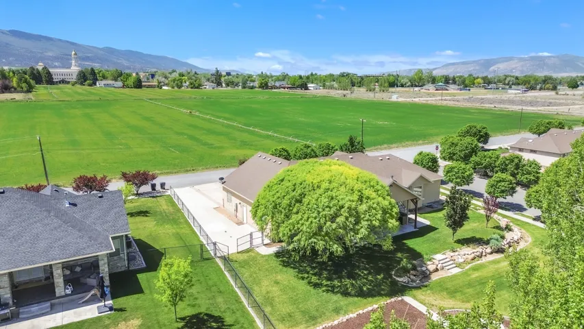 Expansive property featuring a meticulously maintained lawn, mature trees, a paved driveway, and perimeter fencing