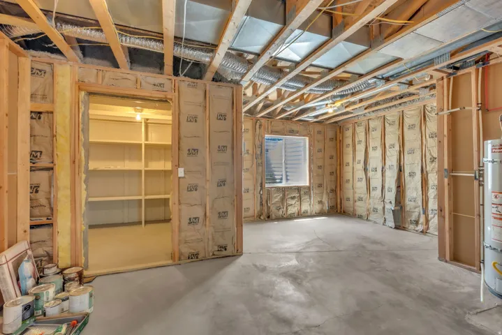 Unfinished basement space featuring exposed wood framing, insulation, and concrete flooring
