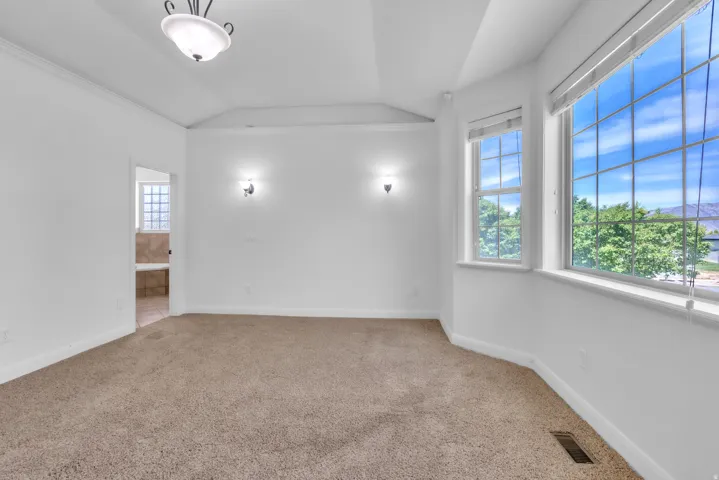 Spacious room featuring multiple large windows, recessed ceiling, wall sconces, and a ceiling-mounted light fixture