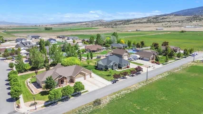 Expansive corner lot featuring a manicured lawn, established landscaping, and a three-car garage