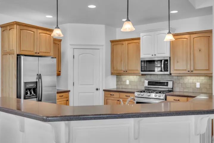 Kitchen featuring a gas range, stainless steel appliances, recessed lighting, pendant lighting, and a breakfast bar