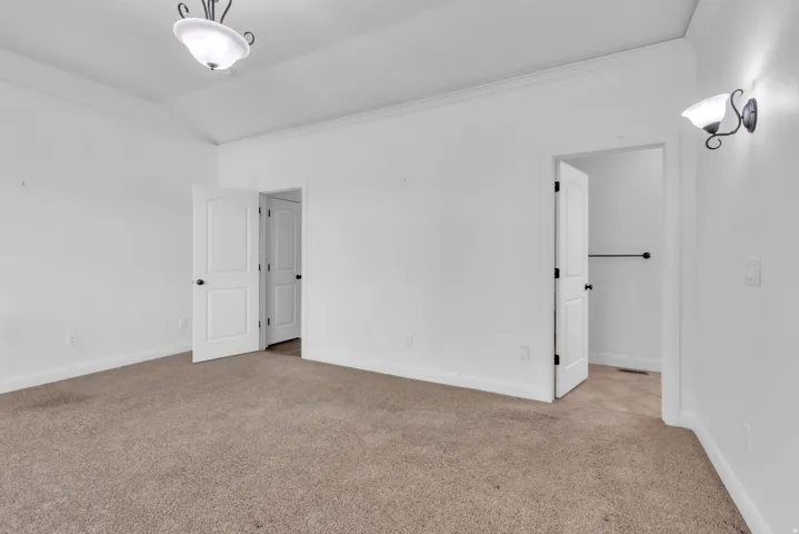 Carpeted room with white walls, two panel doors, and overhead lighting