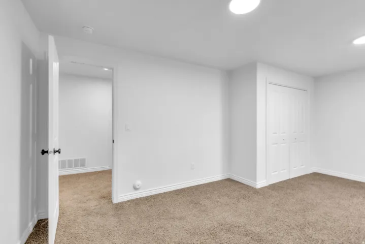 Neutral-toned carpeting and white walls in a room featuring recessed lighting, a bifold closet, and a white interior door with black hardware