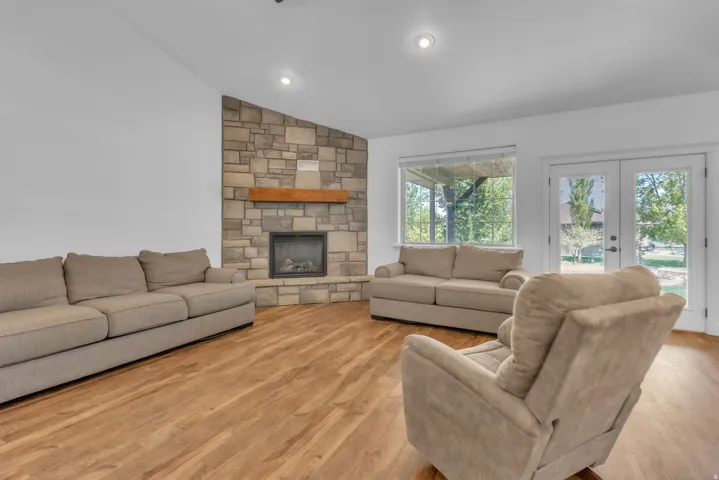 Living area featuring a floor-to-ceiling stone fireplace with a wood mantel, wood-finish flooring, and recessed lighting