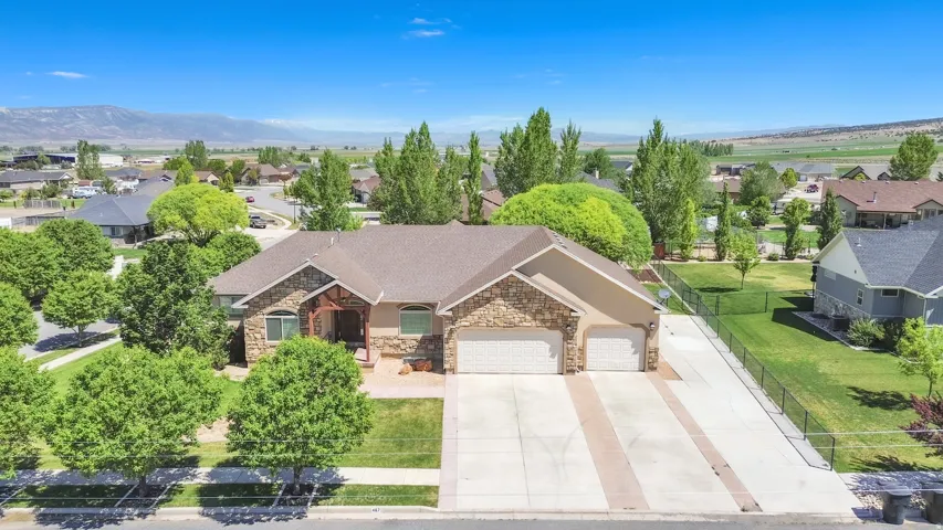 Contemporary residence featuring stone and stucco siding, a multi-car driveway with paver accents, and a dual garage