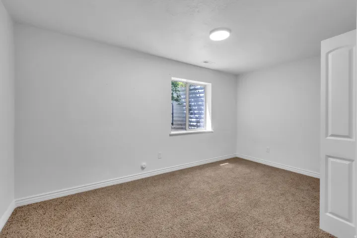 Carpeted room featuring a single window, white baseboards, and a flush-mount ceiling light fixture