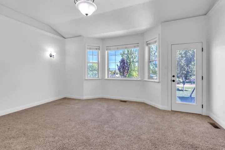 Spacious room featuring a bay window with multiple panes, a glass-paneled exterior door, and a domed ceiling light fixture