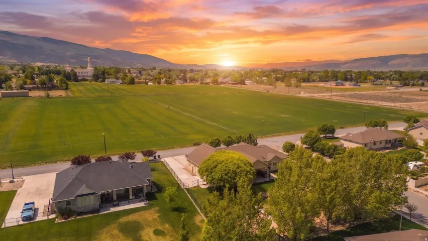 Aerial perspective showcasing the residential area with surrounding green fields and distant mountains