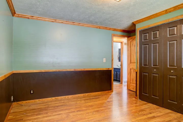 Wood-finish flooring with dark bi-fold closet doors and wood trim