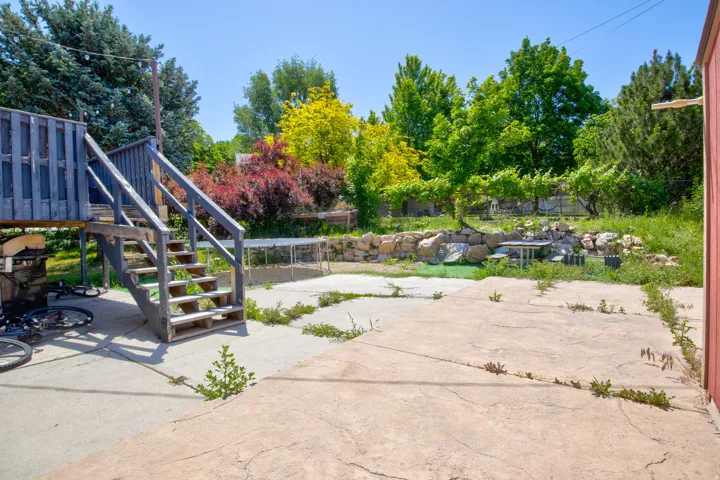 Backyard featuring a multi-level wood deck with stairs, a concrete patio area, and a stone retaining wall