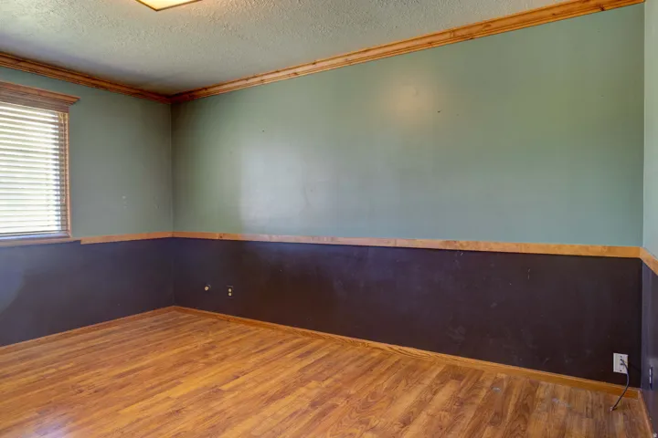 Wood-finish flooring, wood trim details, window with blinds, and ceiling-mounted light fixture
