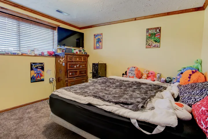 Bedroom featuring warm yellow walls with wood trim and carpeted flooring