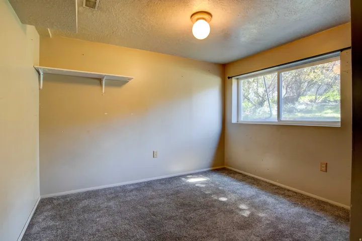 Neutral-toned wall paint, white trim, grey carpeting, and a built-in wall shelf