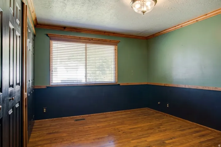 Wood-finish flooring, two-tone wall paint, wood trim accents, and a ceiling-mounted light fixture