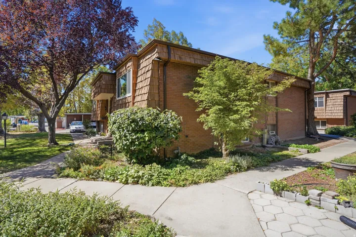 Brick exterior with shake siding accents, mature trees, established landscaping, and paved walkways