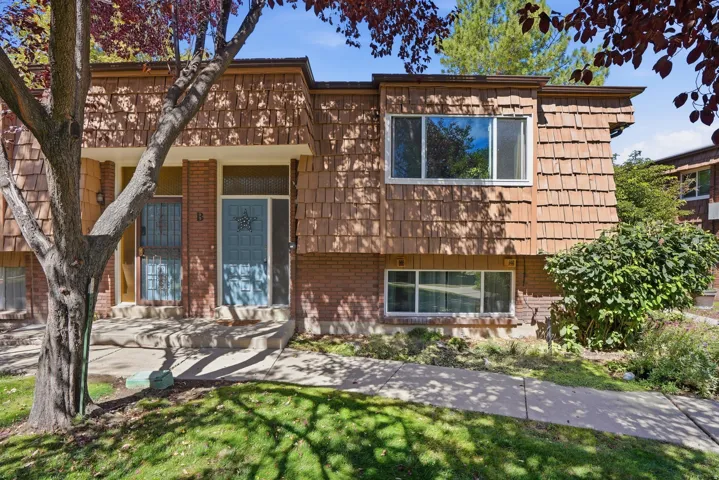 Brick and wood shingle exterior featuring multiple windows and a concrete pathway