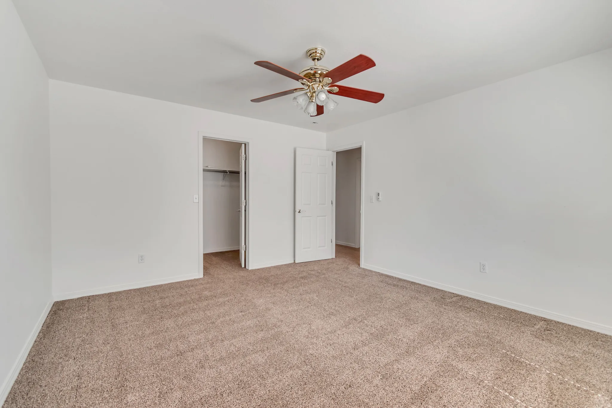 3rd Bedroom with spacious room featuring neutral carpeting, white walls, and a ceiling fan with light fixture