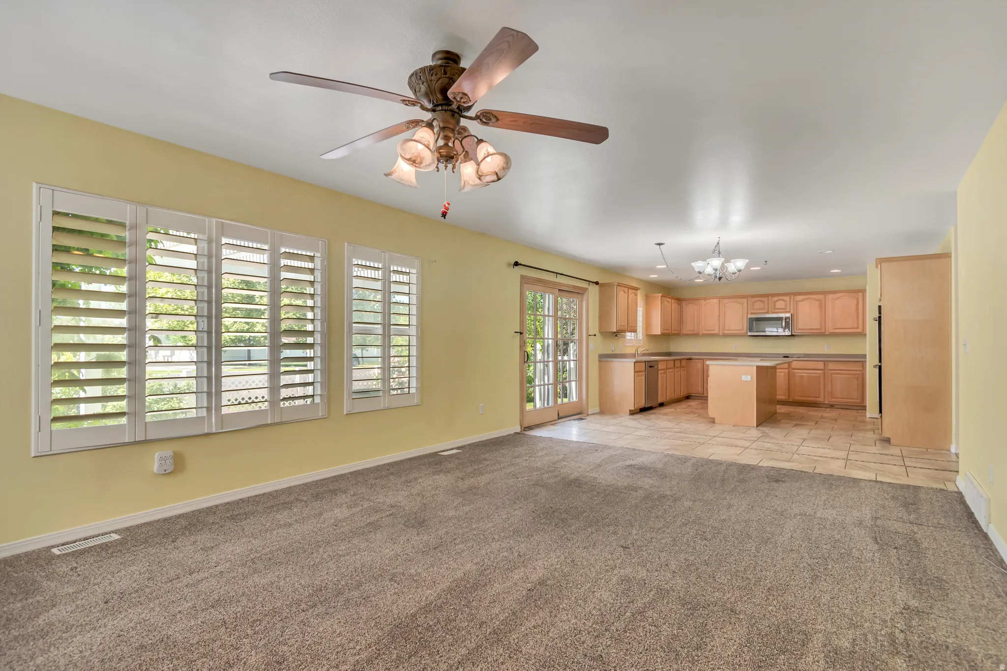 Open-concept area featuring a kitchen with wood cabinetry, a central island, and tile flooring