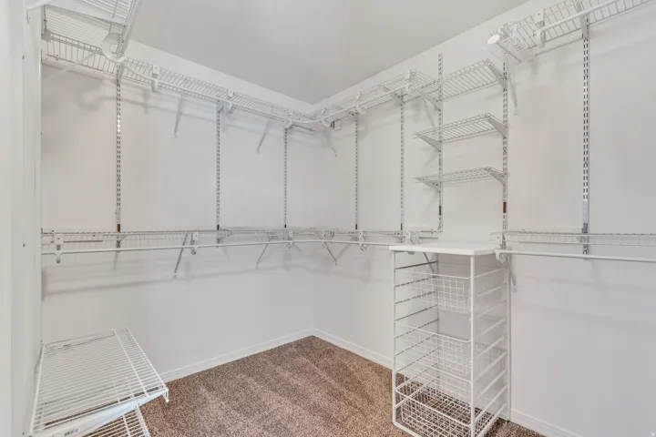 2nd bedroom with spacious walk-in closet featuring white wire shelving, multiple hanging rods