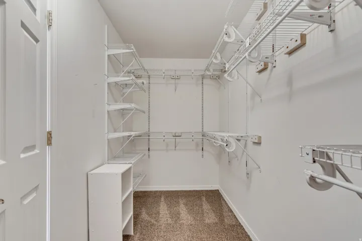 Master walk-in closet with carpet flooring, white wire shelving