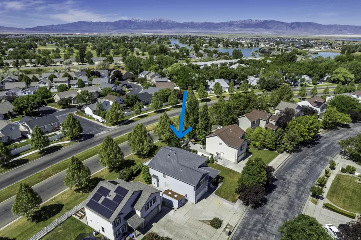 Suburban residential setting with mature trees and paved streets (blue arrow)