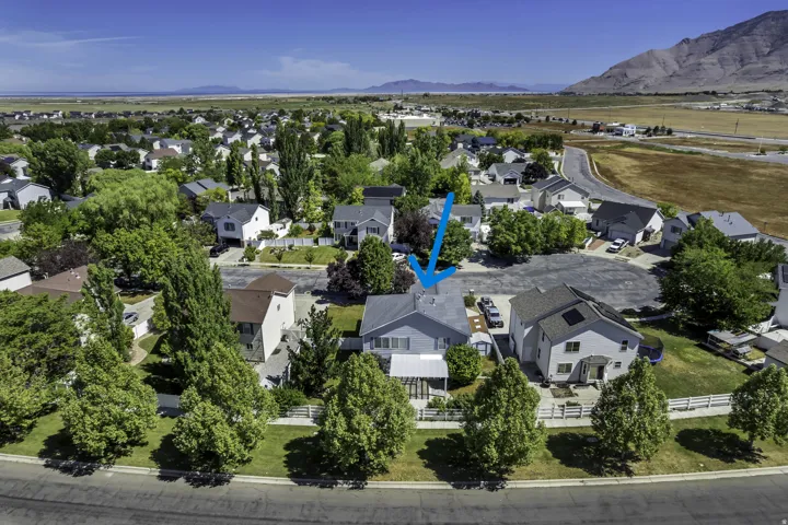 Residential property in a neighborhood setting with established trees and surrounding mountainous terrain (blue arrow)