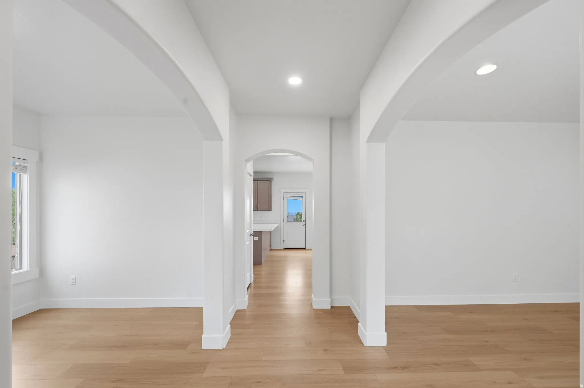 Archway entryways with light wood-finish flooring