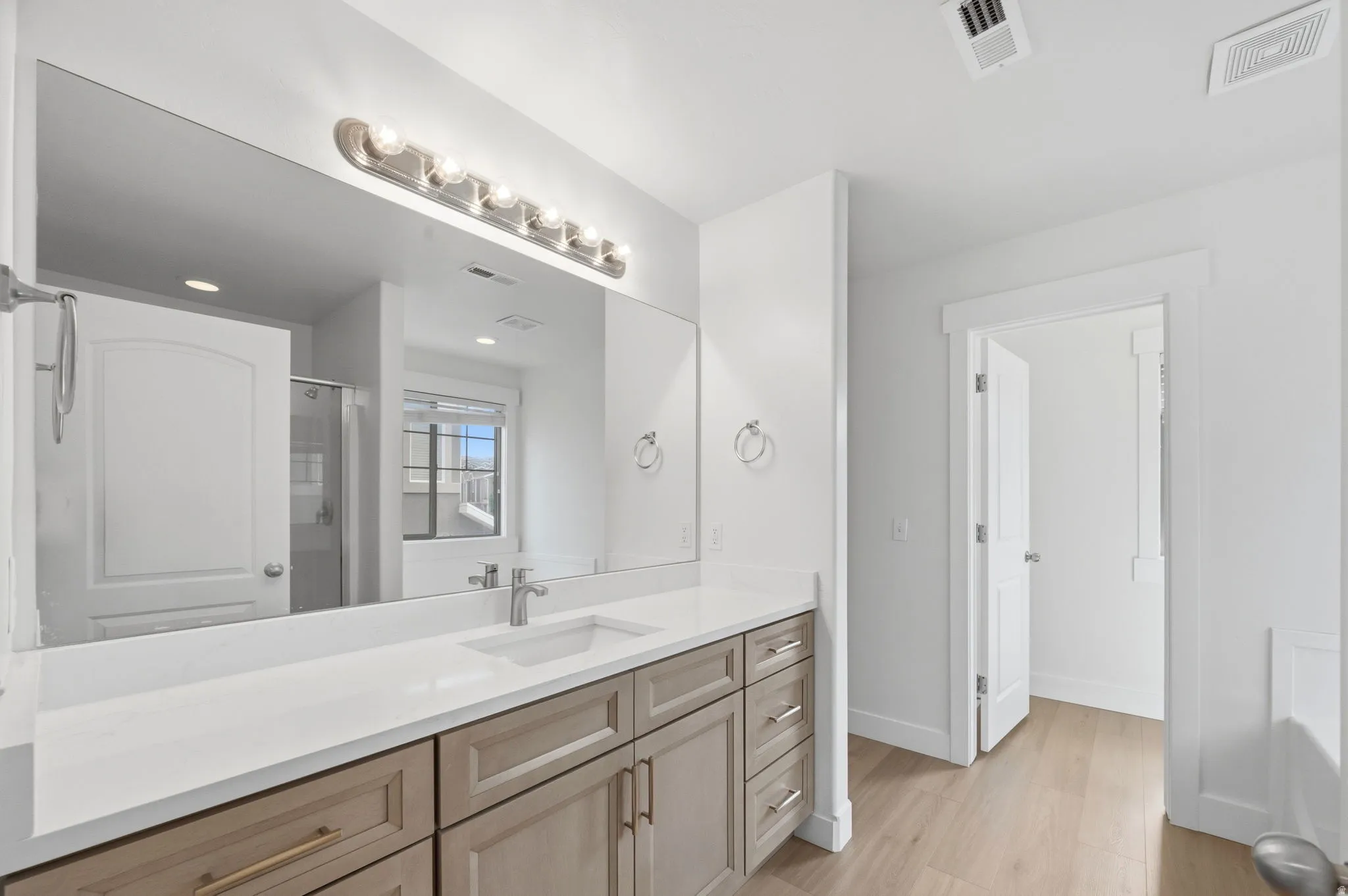 Spacious bathroom featuring an extended vanity with soft-close cabinetry, a single undermount sink, and private doored toilet.