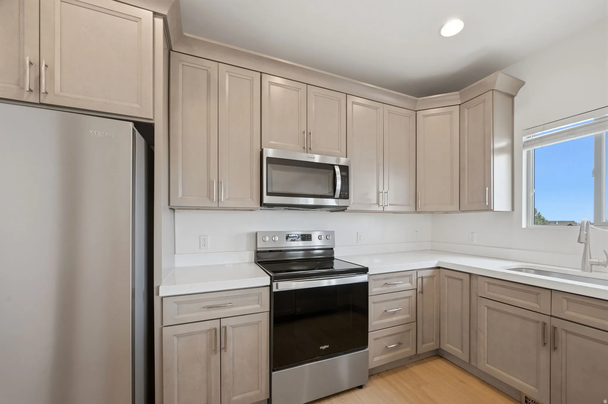 Modern kitchen featuring light wood-finish cabinetry, stainless steel appliances and Quartz countertops.
