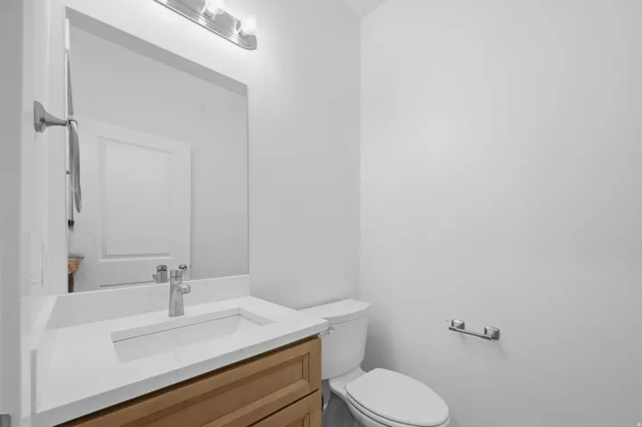 Main level 1/2 Bath Modern vanity featuring wood-finish cabinetry, a white countertop with an integrated rectangular sink.