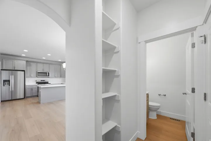 Archway entry to a modern kitchen featuring stainless steel appliances, soft-close cabinetry, and a center island with a white Quartz countertop