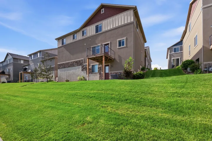 Multi-level rear exterior featuring a deck with metal railing, stucco siding, and stone accents
