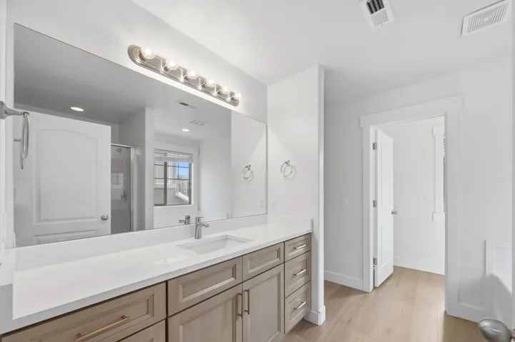 Spacious bathroom featuring an extended vanity with soft-close cabinetry, a single undermount sink, and private doored toilet.