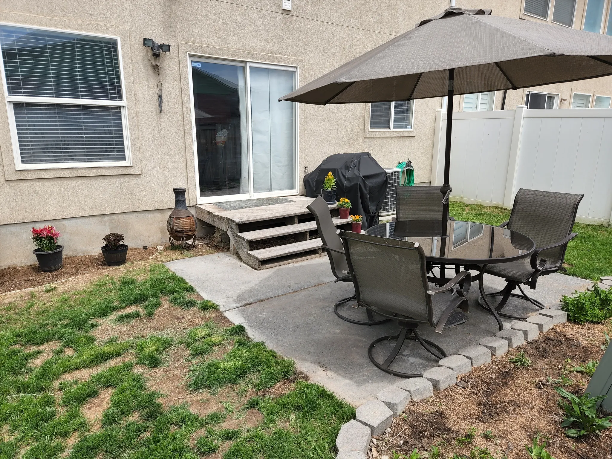 Exterior patio area featuring a concrete pad, a stepped wooden deck, and a sliding glass door. This is a former picture...no grass currently.