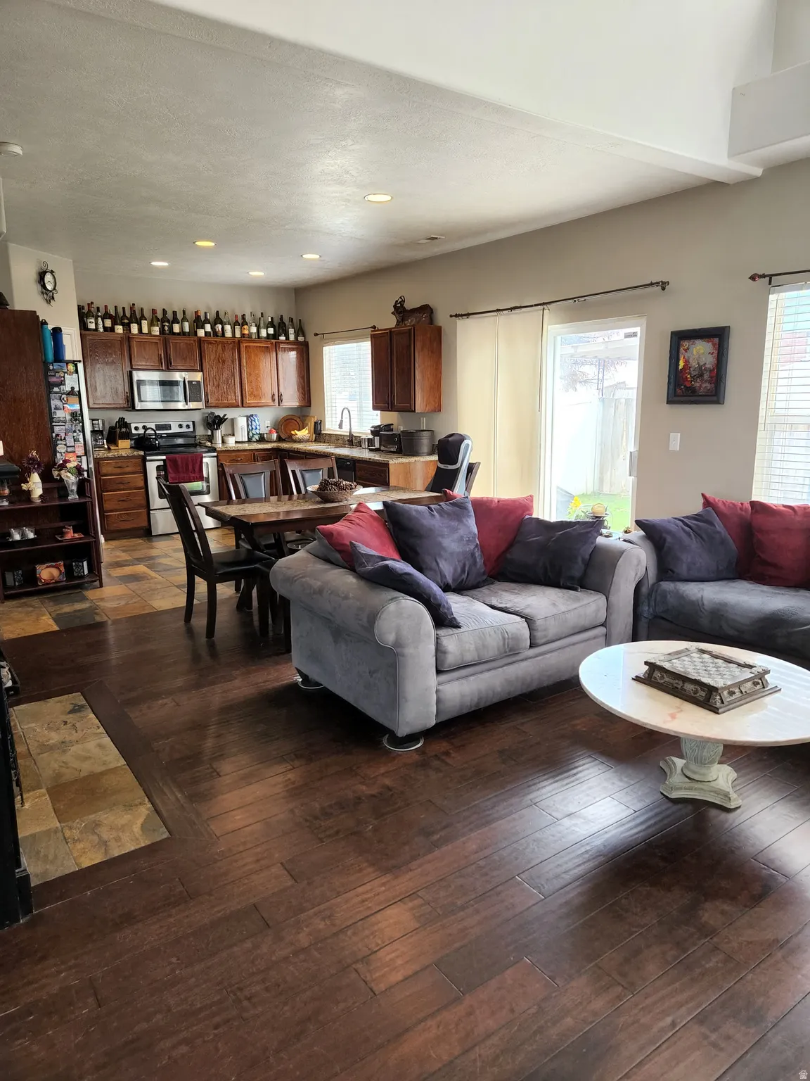 Open-concept living area featuring rich wood-finish flooring, recessed lighting, and a sliding glass door to the exterior