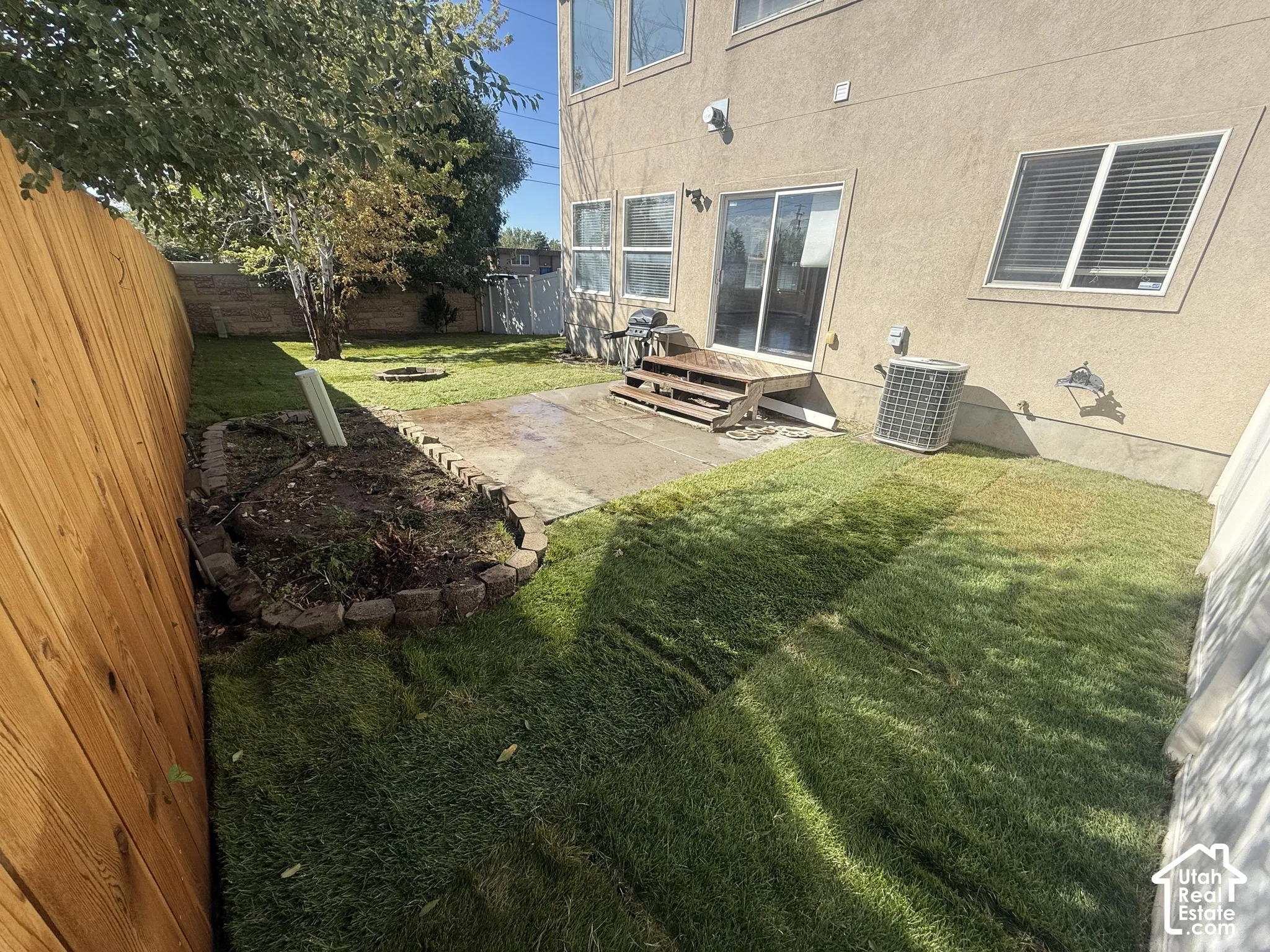 Private backyard featuring newly installed sod, a wood privacy fence, and a concrete patio with a sliding glass door