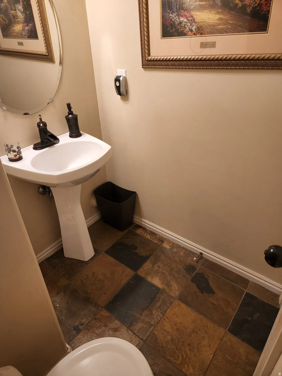 Pedestal sink with a wall-mounted faucet, complemented by multi-toned square slate floor tiles in main floor half bathroom