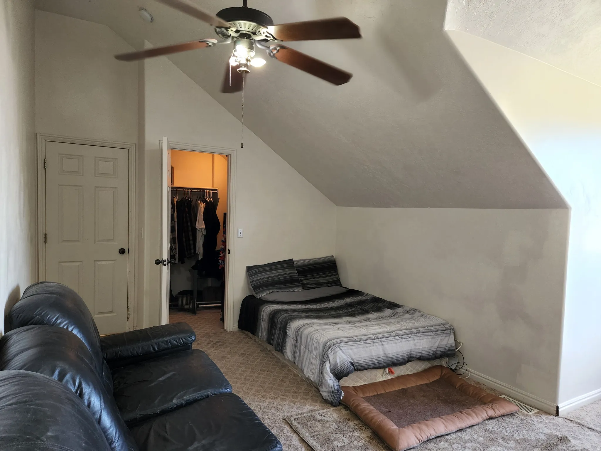 4th bedroom featuring sloped ceilings, a ceiling fan with light, and a dedicated walk in closet with built-in shelving