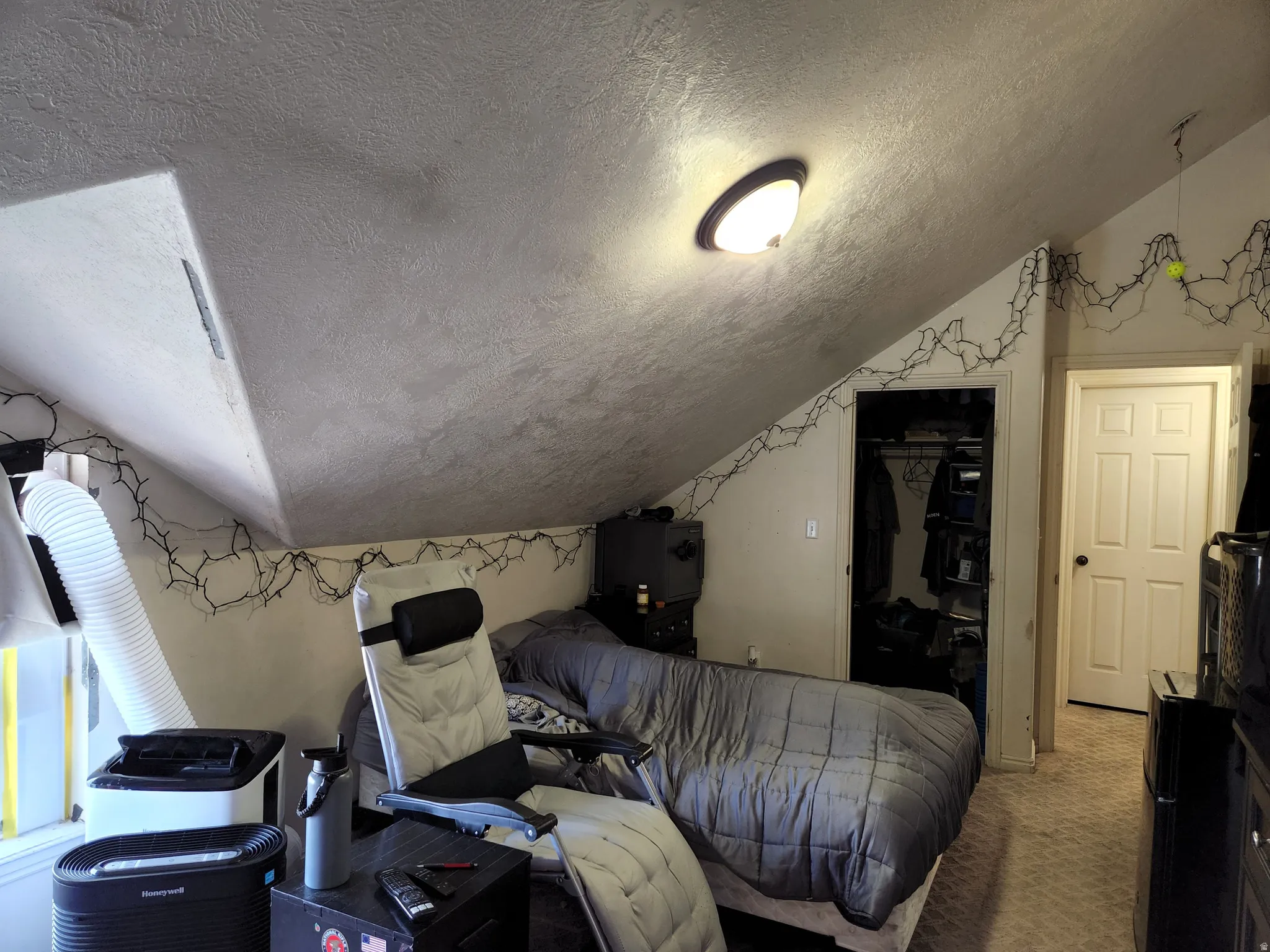 5th bedroom with Angled ceiling with textured finish, flush-mount ceiling light fixture, window with white trim, built-in closet with shelving, and a six-panel interior door