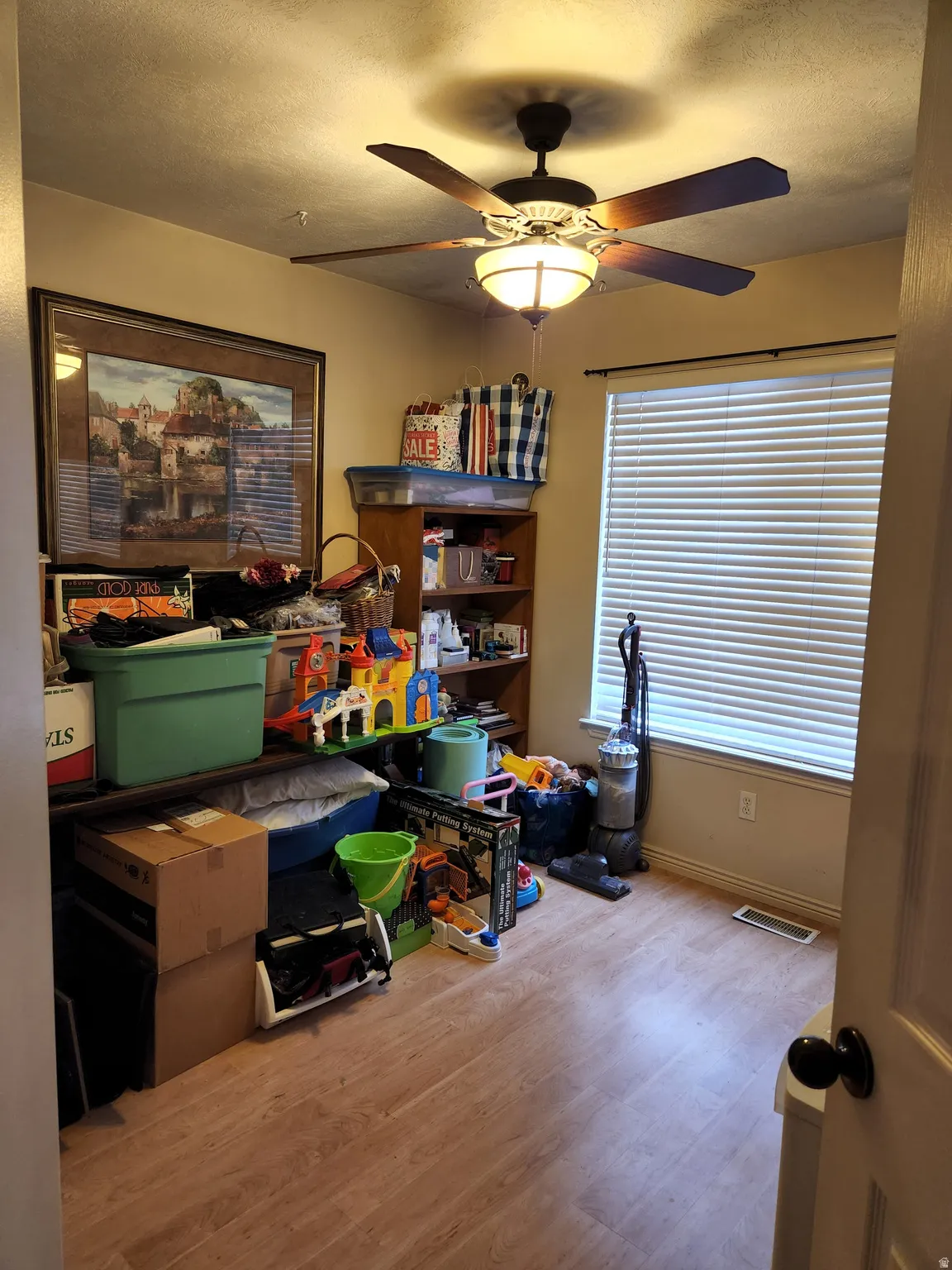 3rd bedroom featuring wood-finish flooring, a ceiling fan with integrated lighting, and a single window with horizontal blinds