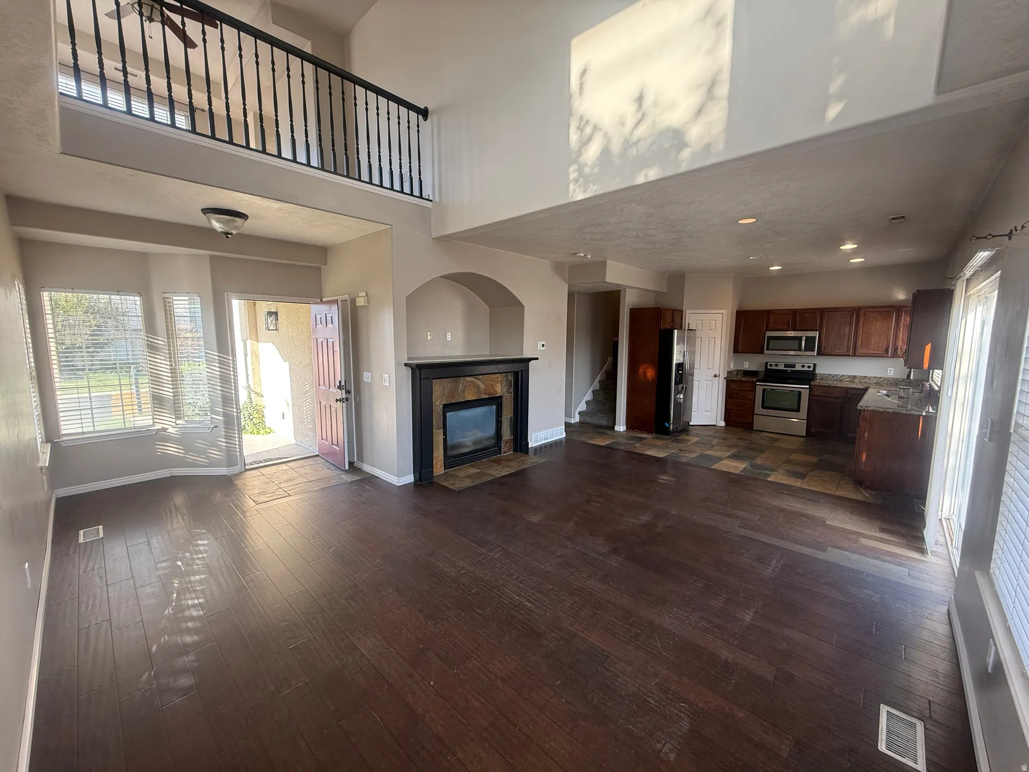 Two-story living area with wood-finish flooring and an open second-story hallway with a black spindle railing
