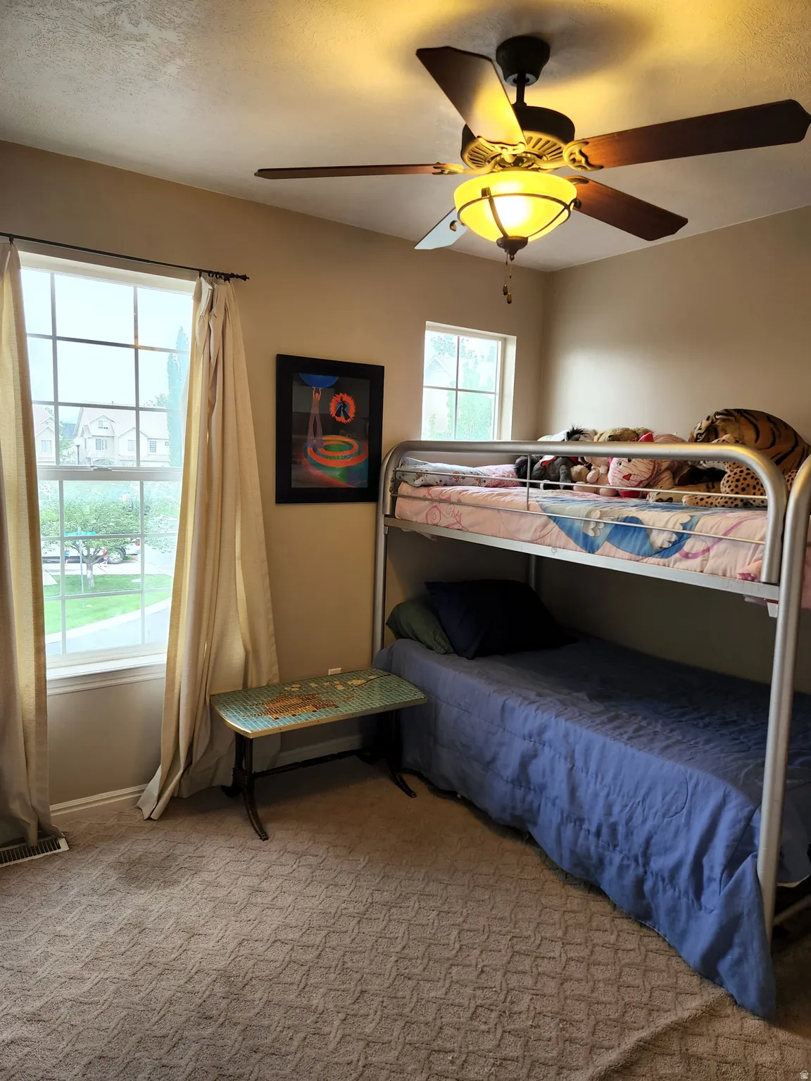 2md bedroom with carpet, a ceiling fan light fixture, two windows, and a built-in air vent