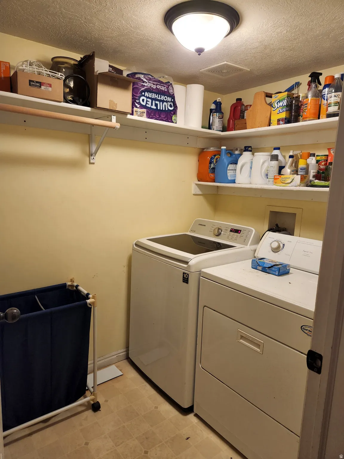 Dedicated laundry area featuring a washer, dryer, and overhead shelving for organization