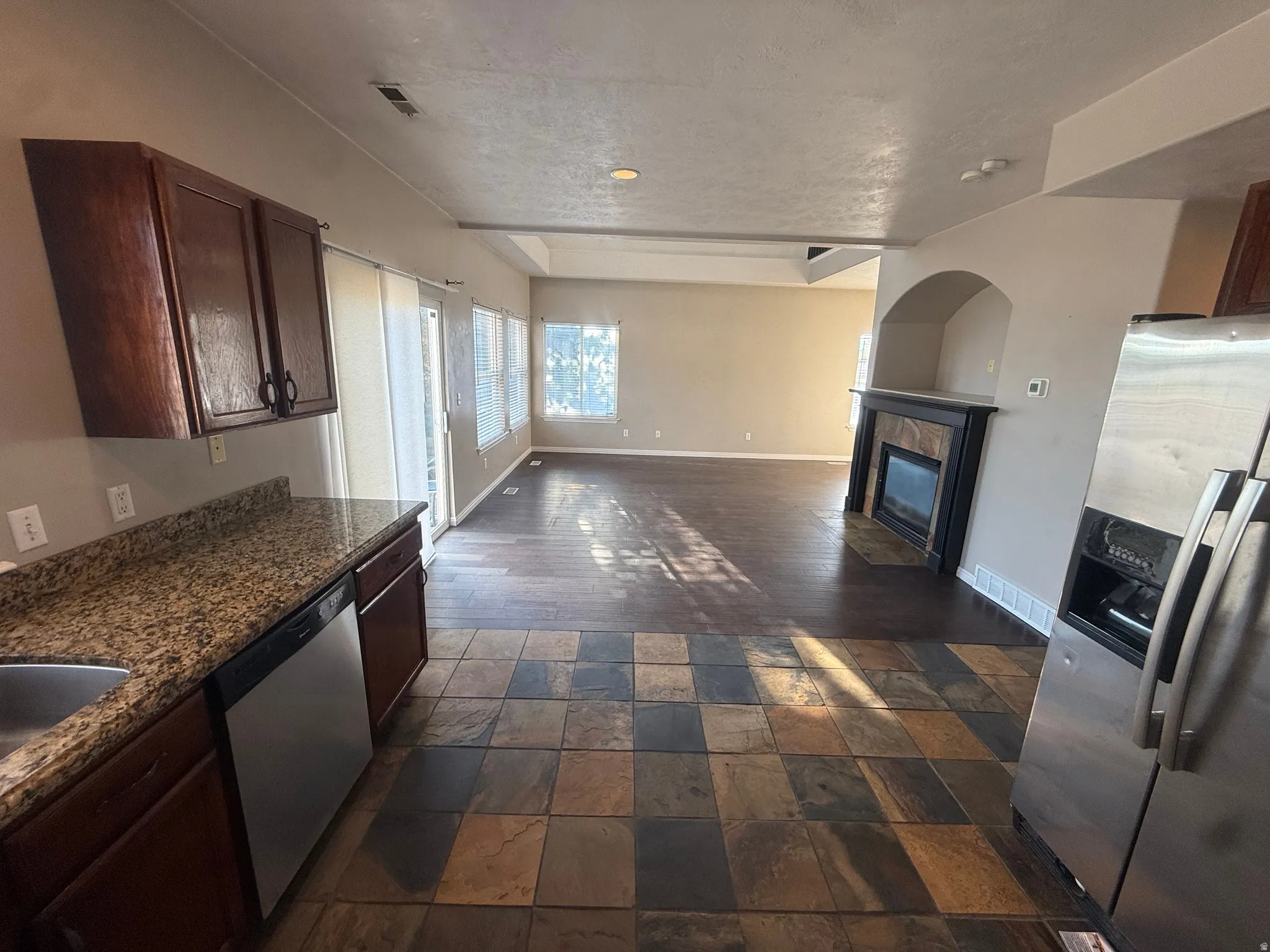 Kitchen with stone tile flooring, granite countertops, and dark wood cabinetry