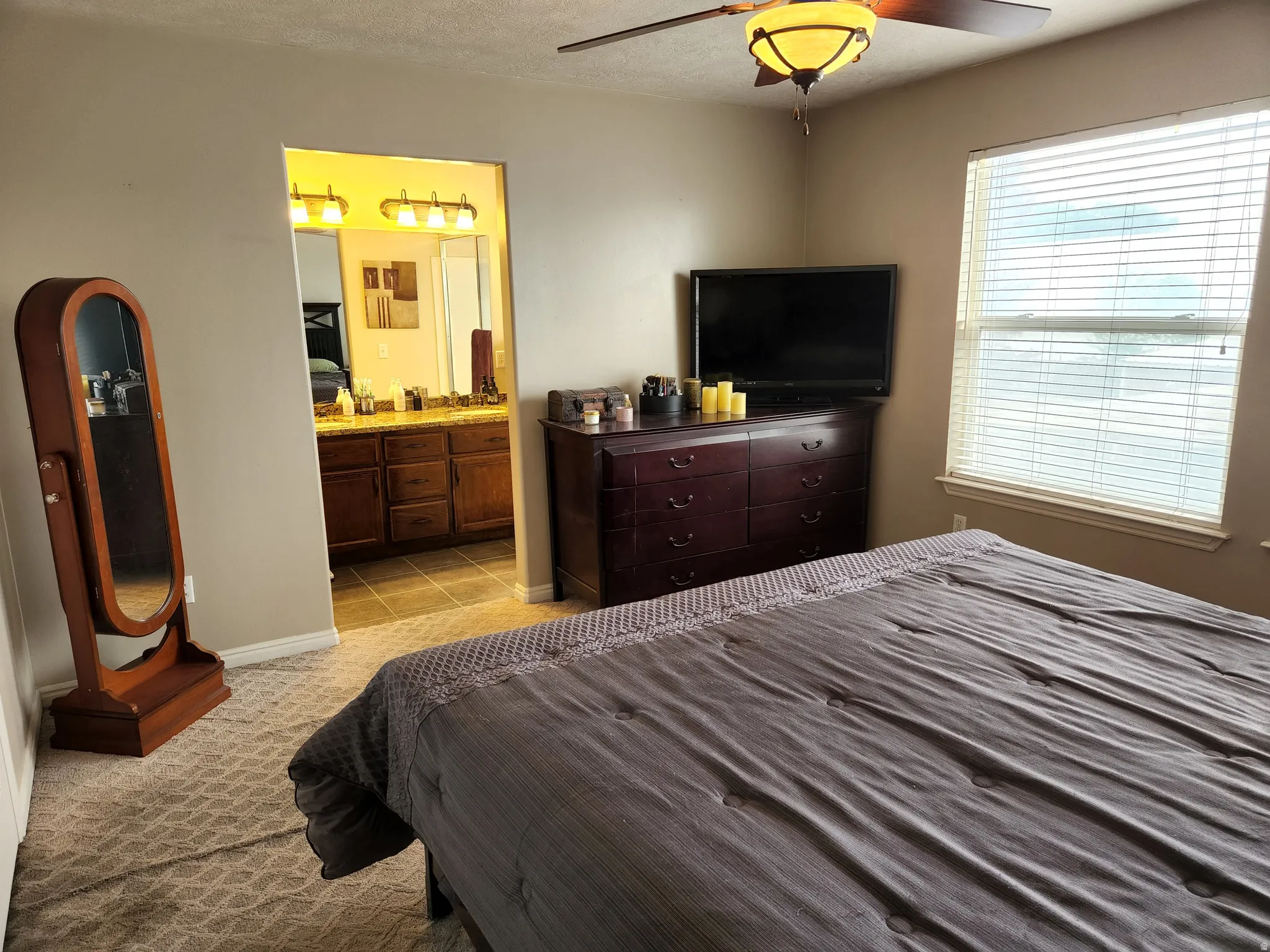 Master bedroom featuring patterned carpeting and a ceiling fan with integrated lighting